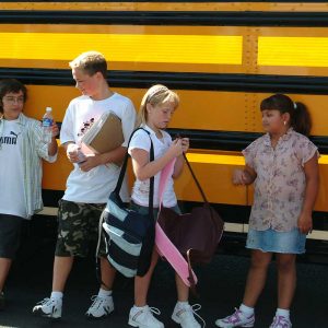 Students wait to get on a bus