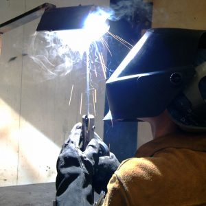 A Magnet high school student welds pieces together