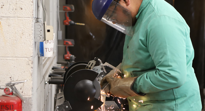 A student grinds a piece of metal during an apprenticeship summit showcase