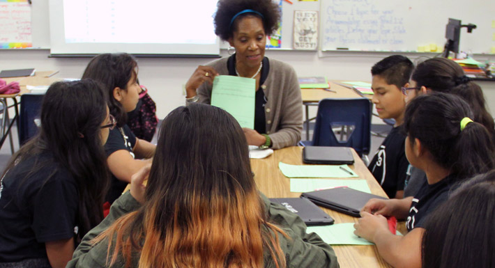 A teacher instructs a table full of students