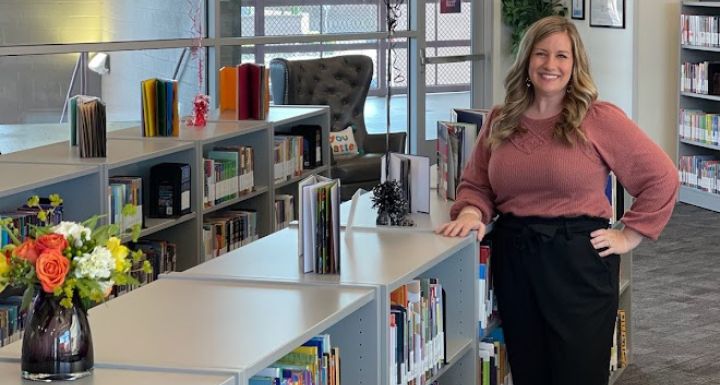 A CCSD librarian poses in front of books inside the school library.