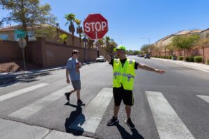 One of the many school crossing guards manages traffic after school near a CCSD middle school.