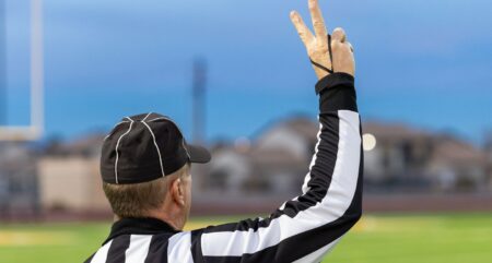 A referee prepares for the next play during a high school sporting event.